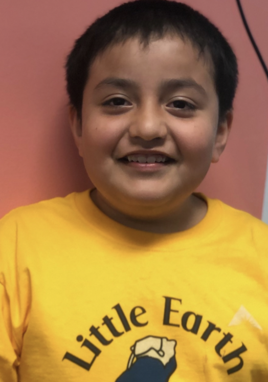 Boy smiling in a yellow shirt that says "little earth"